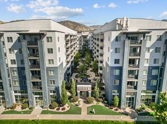 A large apartment complex with a green lawn in the middle.