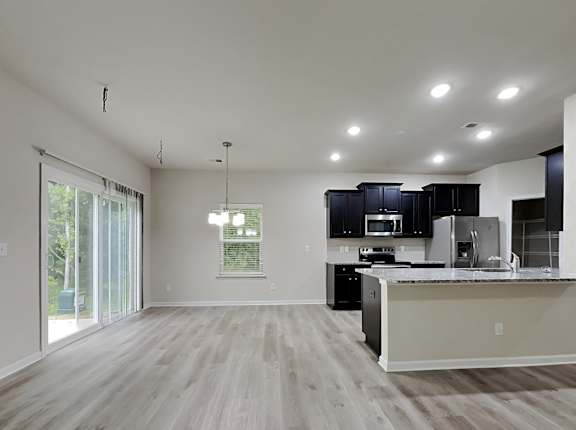 an open kitchen and living room with a sliding glass door to a patio