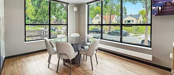 A dining room with a table and chairs with a view of the street outside.