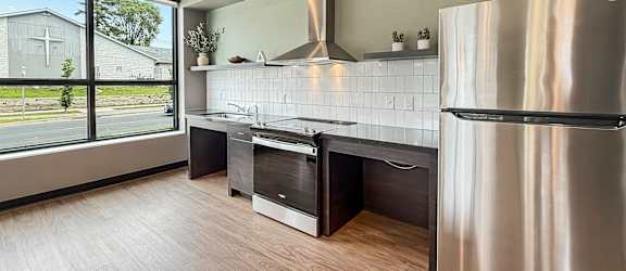 A modern kitchen with a stainless steel refrigerator and wooden flooring.