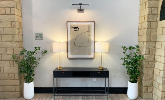 a modern entryway with a black console table and white vases with green plants