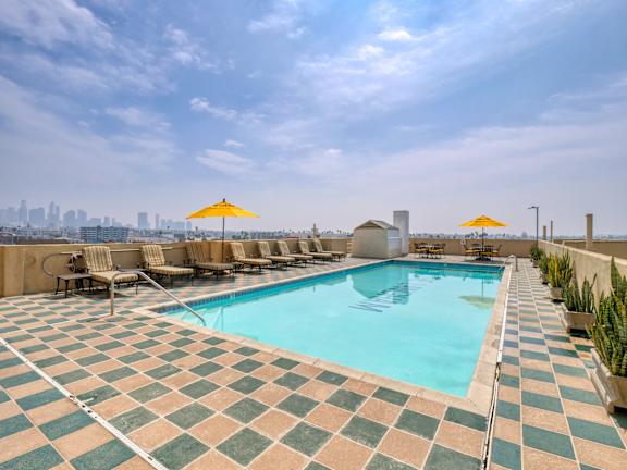 Swimming pool with tiled floor and relaxing chairs at The Langham Apartments, Los Angeles, 90005