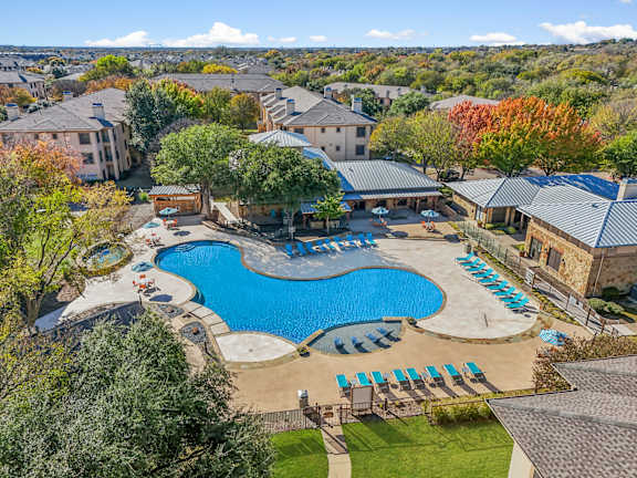 A large swimming pool surrounded by a grassy area and trees.