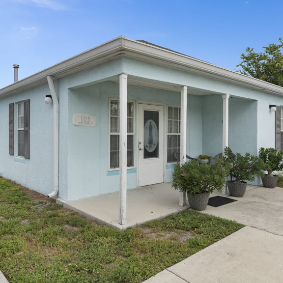 a light blue house with a porch and a sidewalk at The Groves at Wimauma Apartments , Wimauma, Florida