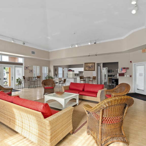 A living room with a red couch and wicker chairs. at The Groves at Wimauma Apartments , Wimauma, Florida