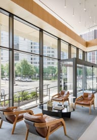 a lobby with chairs and a table in a building with large windows at The Lively, New Jersey, 07302