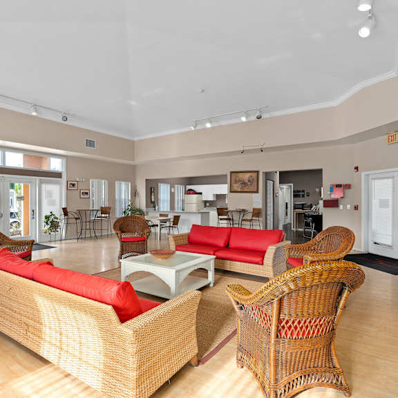 A living room with a red couch and wicker chairs. at The Groves at Wimauma Apartments , Wimauma, Florida
