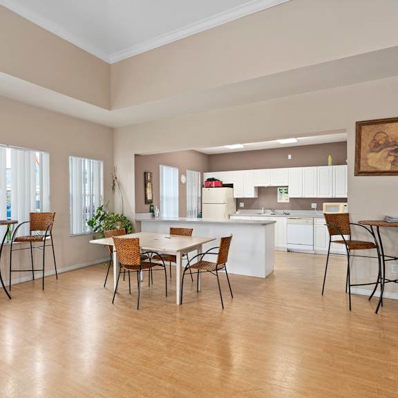 A kitchen with a table and chairs in the foreground. at The Groves at Wimauma Apartments , Wimauma, Florida