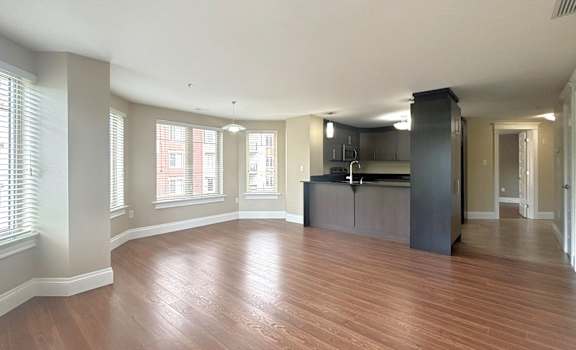 A spacious room with wooden flooring and a kitchen island.