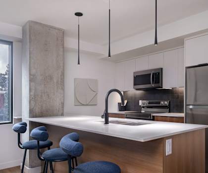 A modern kitchen with a bar area and blue stools.