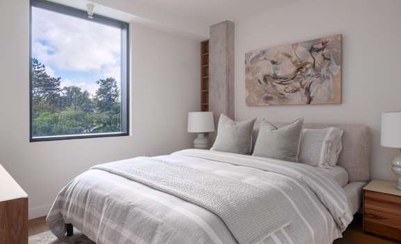 A bedroom with a large bed and a painting on the wall.