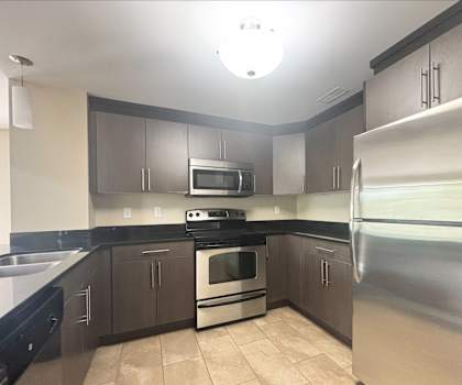 A kitchen with a stove, oven, refrigerator, and microwave.