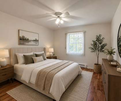 A bedroom with a large bed, a ceiling fan, and a painting on the wall.