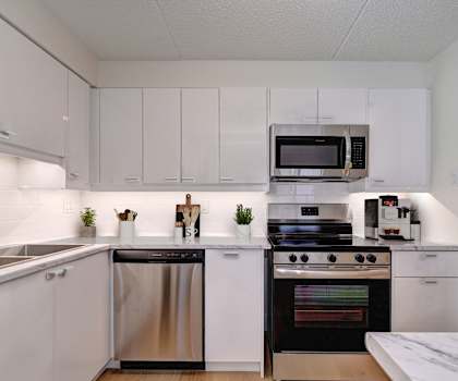 A modern kitchen with white cabinets and stainless steel appliances.