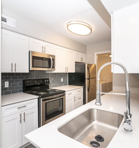 a kitchen with white cabinets and black appliances and a sink