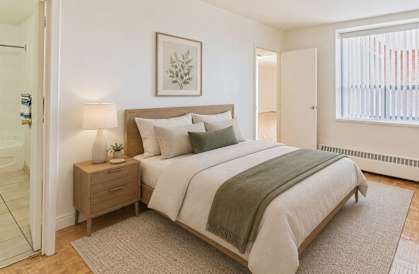A bedroom with a bed, nightstand, and lamp.
