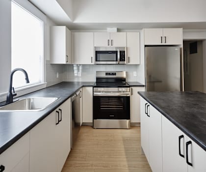 A modern kitchen with white cabinets and black countertops.