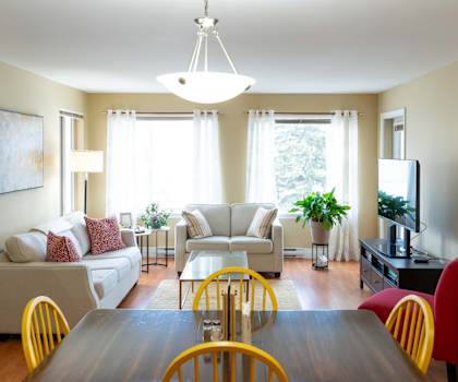A well-lit living room with a dining table and chairs.