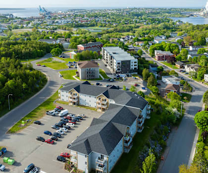 A parking lot in front of a building with a large body of water in the background.