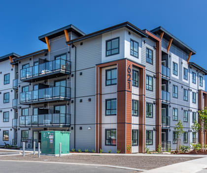 A modern apartment building with a mix of grey, brown, and blue tones.