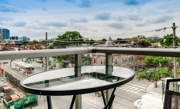 A glass table with a metal frame is in the foreground of a city street scene.