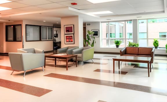 A spacious waiting room with a variety of seating options and a view of the outside.