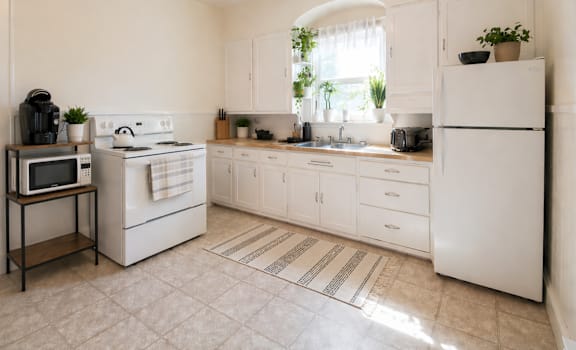 A white kitchen with a microwave on a stand.