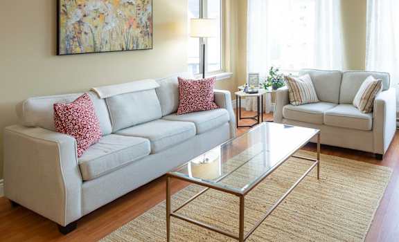 A living room with a white couch and a glass coffee table.