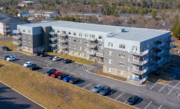 A large grey building with a parking lot in front of it.