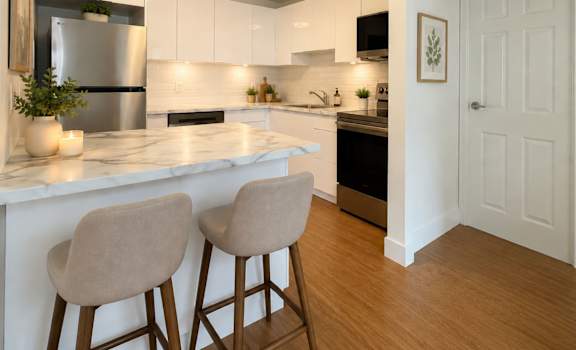 A kitchen with white cabinets and a marble countertop.