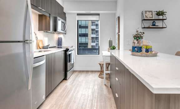 A modern kitchen with a white countertop and stainless steel appliances.