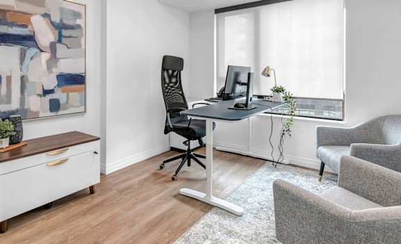 A room with a desk, chair, and a painting on the wall.
