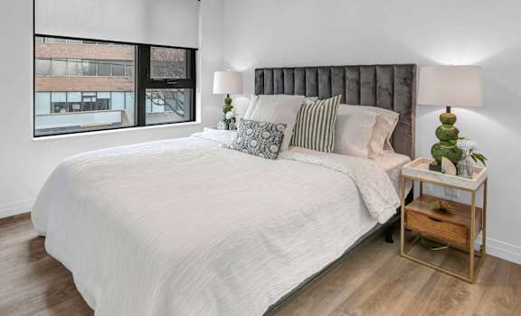 A bedroom with a large bed and a window with blinds.