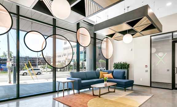A modern office lobby with a blue sofa and a wooden coffee table.