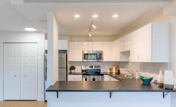 A modern kitchen with a black countertop and white cabinets.