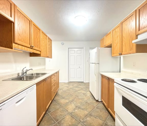 A modern kitchen with a stainless steel refrigerator and wooden flooring.