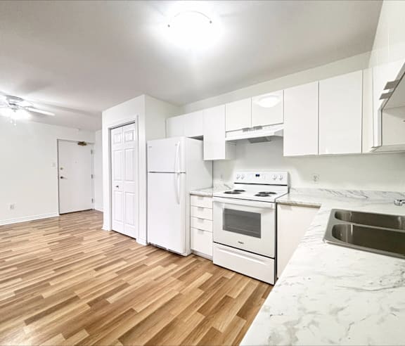 A modern kitchen with a stainless steel refrigerator and wooden flooring.