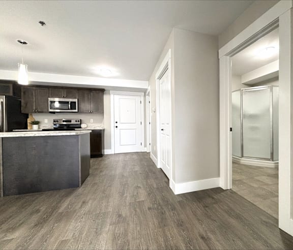 A modern kitchen with a stainless steel refrigerator and wooden flooring.
