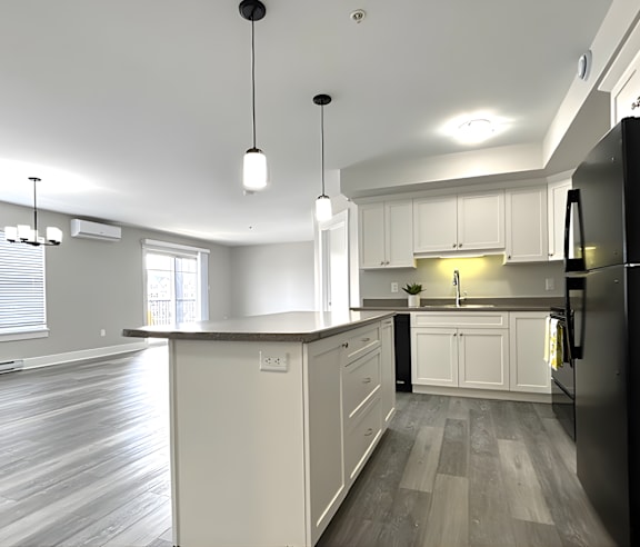 A modern kitchen with a stainless steel refrigerator and wooden flooring.