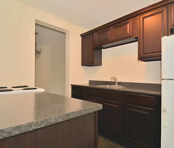 A modern kitchen with a stainless steel refrigerator and wooden flooring.