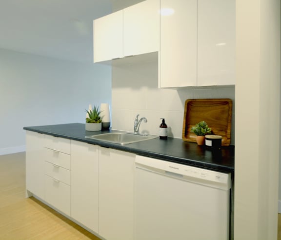 A modern kitchen with a stainless steel refrigerator and wooden flooring.
