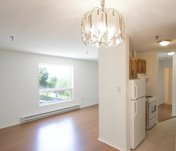 A modern kitchen with a stainless steel refrigerator and wooden flooring.
