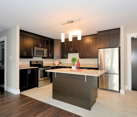A modern kitchen with a stainless steel refrigerator and wooden flooring.