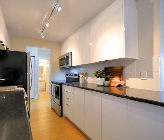 A modern kitchen with a stainless steel refrigerator and wooden flooring.