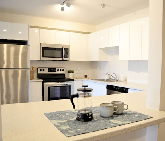 A modern kitchen with a stainless steel refrigerator and wooden flooring.