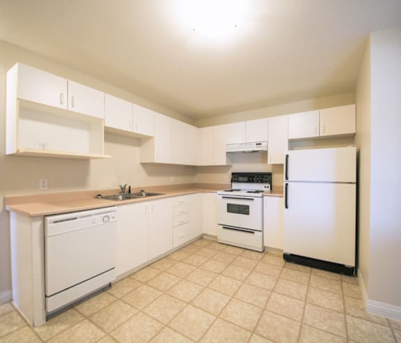 A modern kitchen with a stainless steel refrigerator and wooden flooring.