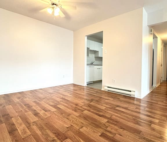 A modern kitchen with a stainless steel refrigerator and wooden flooring.