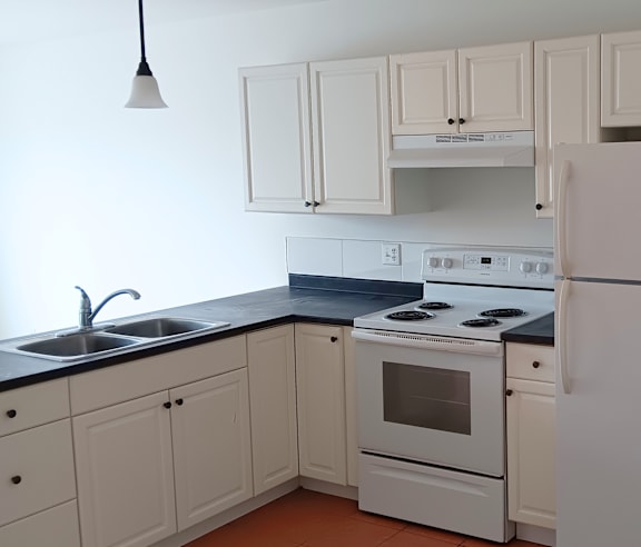 A modern kitchen with a stainless steel refrigerator and wooden flooring.