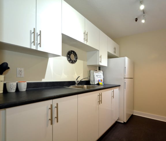 A modern kitchen with a stainless steel refrigerator and wooden flooring.