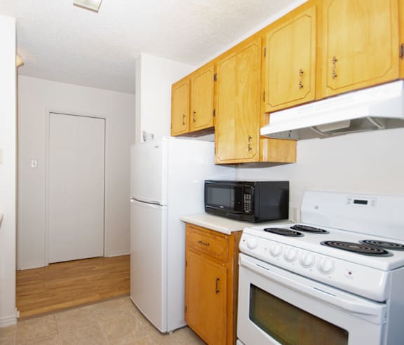 A modern kitchen with a stainless steel refrigerator and wooden flooring.